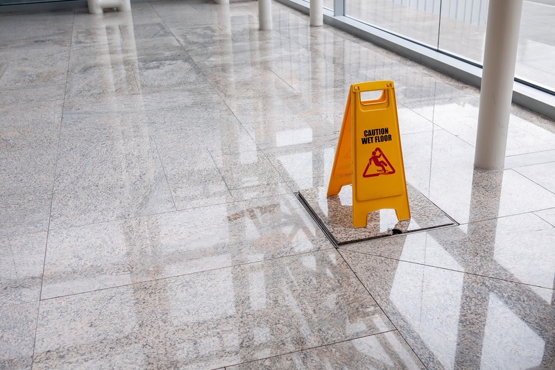 A yellow caution sign on the floor of an office building.